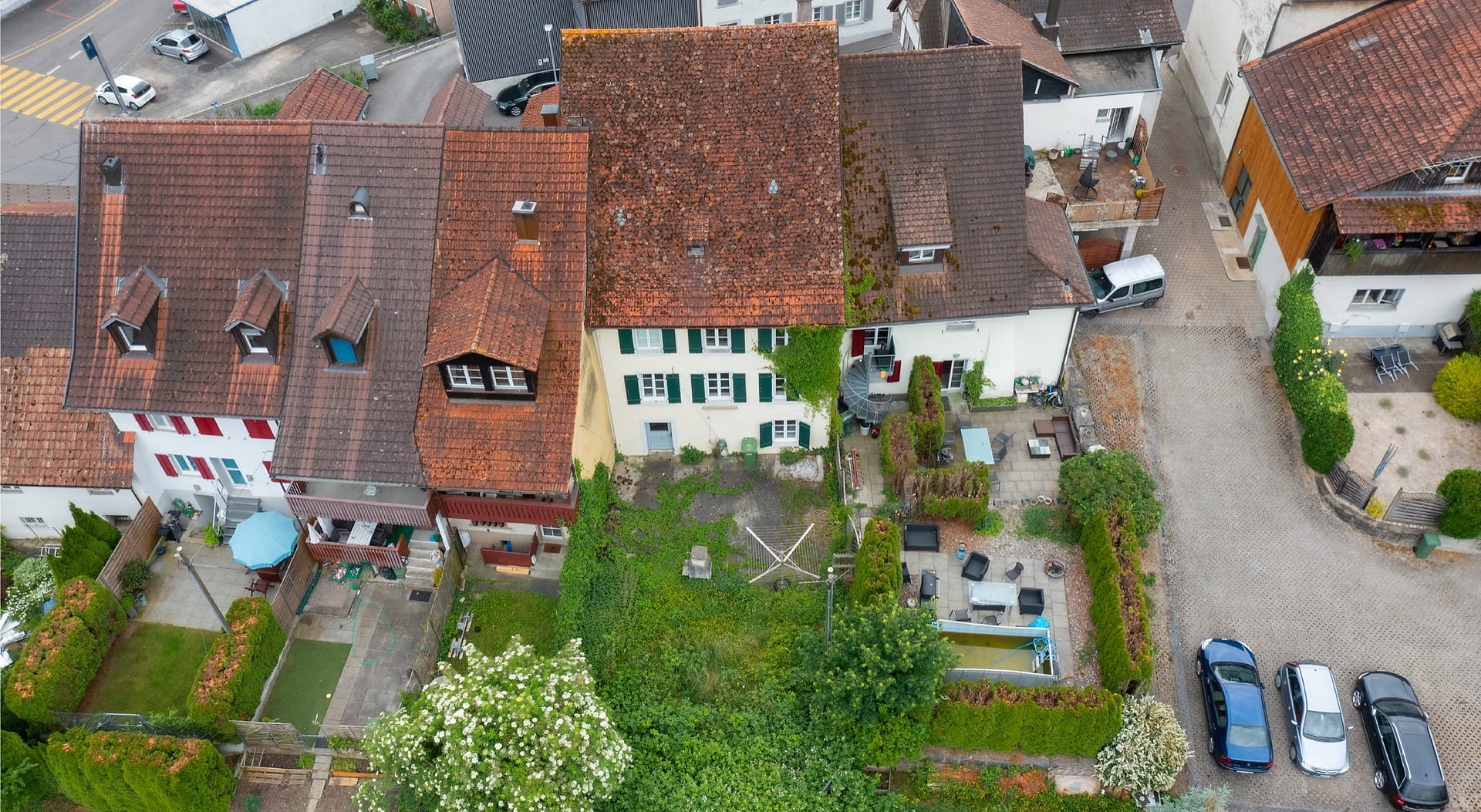 Drohnenaufnahme des historischen Altstadthauses WEIER II in Klingnau: rotes Ziegeldach, grüne Fensterläden, Garten im Bestand