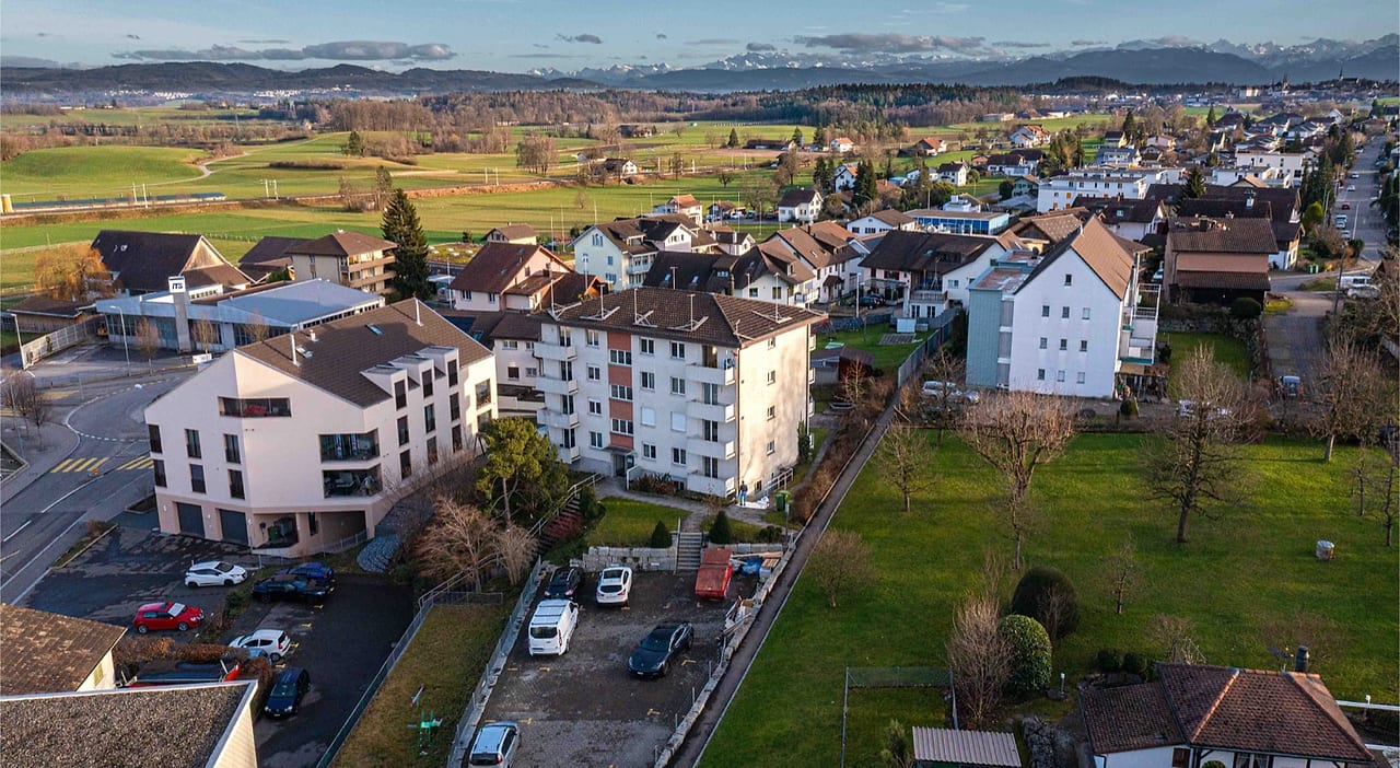 Mehrfamilienhaus ZENTRA in Boswil aus der Luft, eingebettet in Wohnhaeuser und Felder